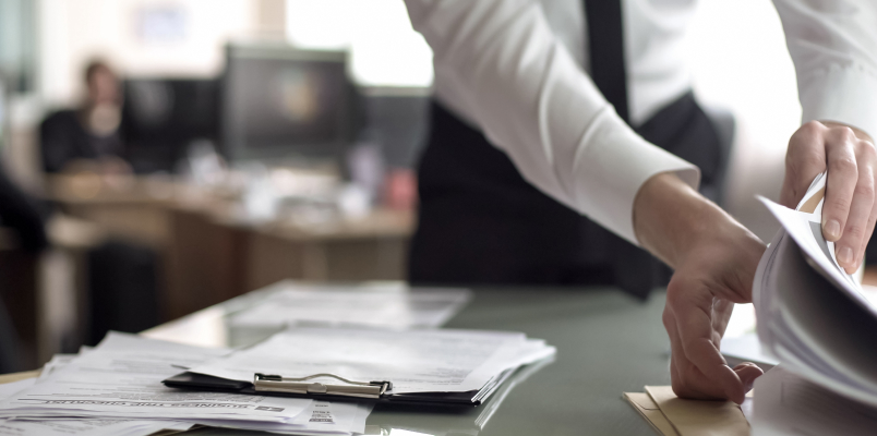 Person sorting through paperwork at a desk while dealing with missing tax documents.