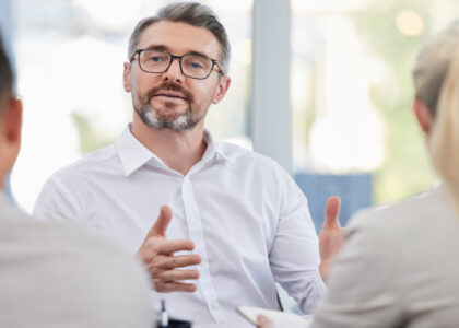 Tax professional explaining small business tax guidance to two clients in a bright office meeting.