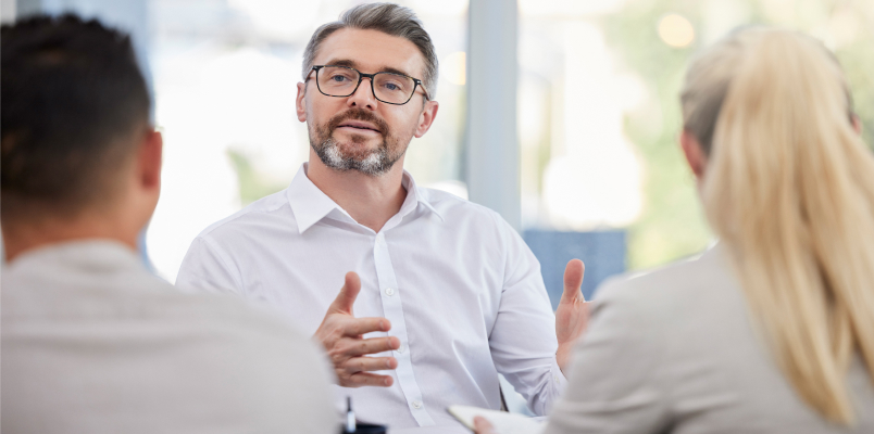 Tax professional explaining small business tax guidance to two clients in a bright office meeting.